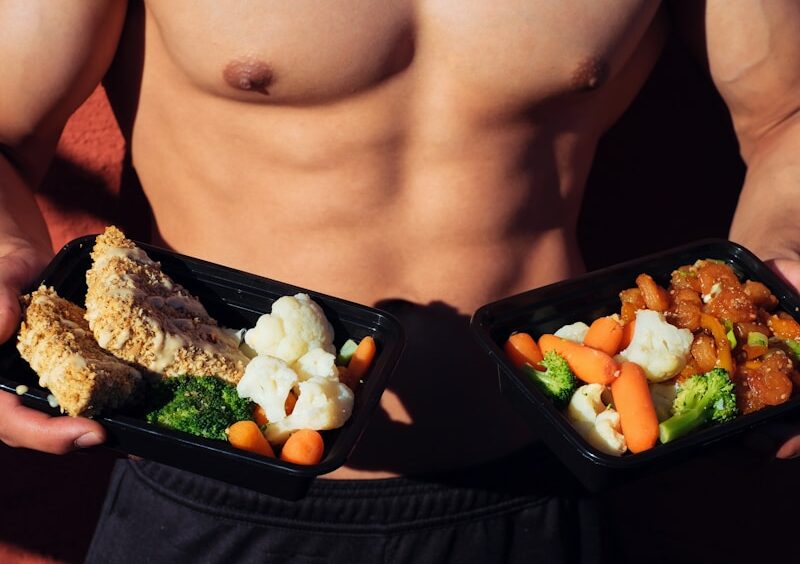 topless man in black shorts holding cooked food