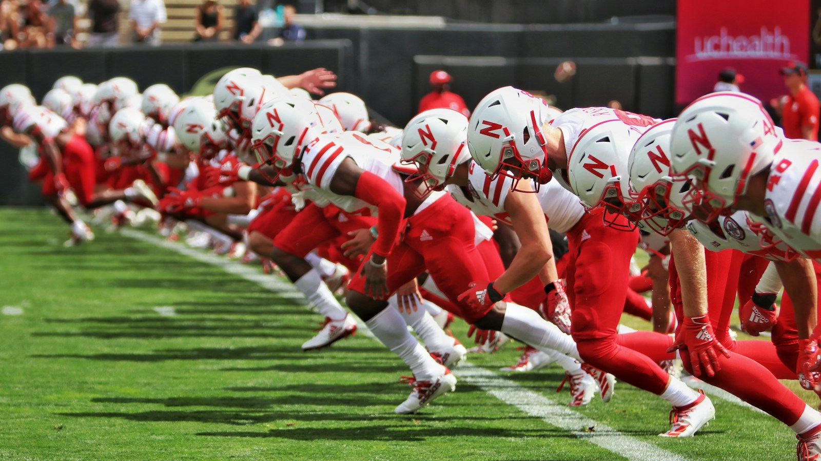 football players in red and white uniform on green field during daytime